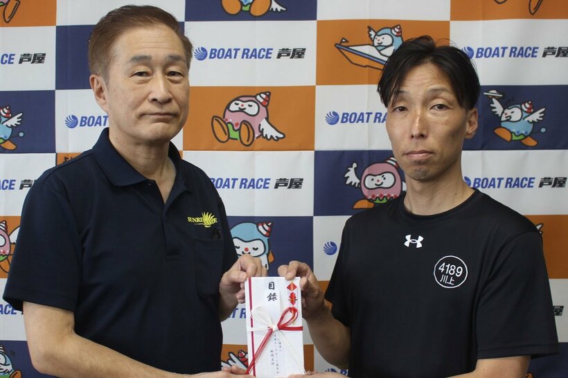 川上剛（右）が芦屋町モーターボート競走事業の藤崎隆好管理者に目録を手渡した