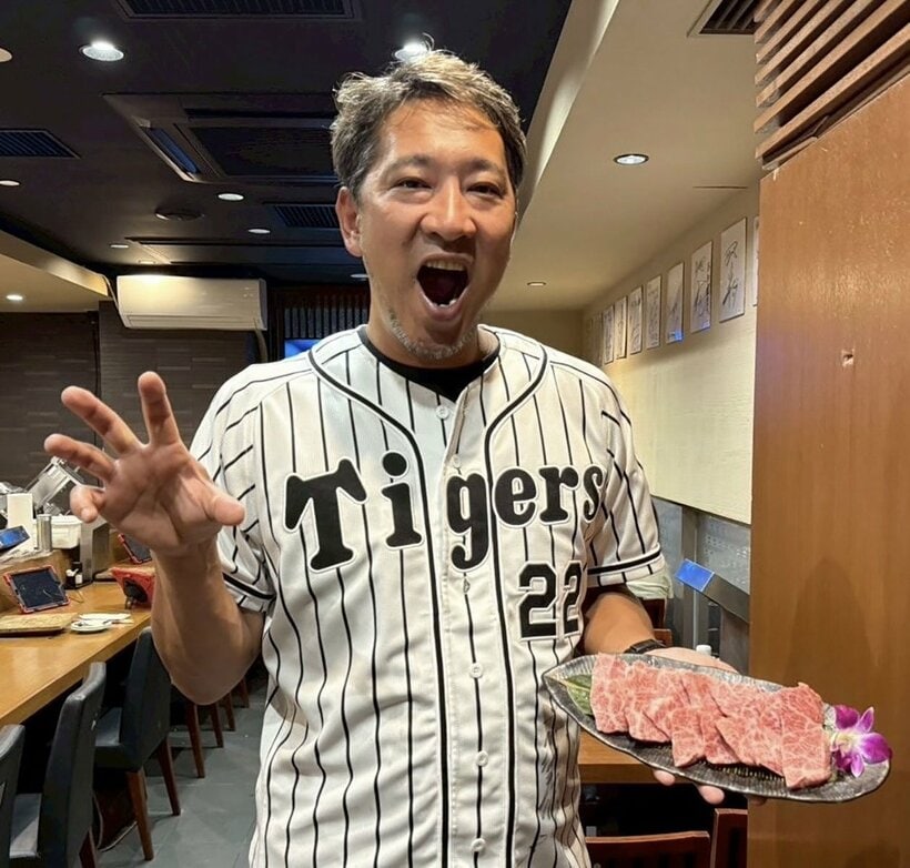 藤川監督のユニホームを着ながら、肉をアピールする阪神のOB投手の加藤隆行さん