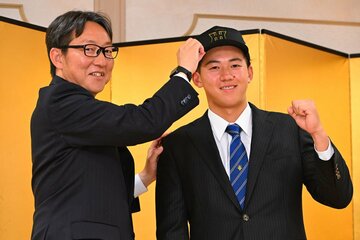 阪神・東辰弥編成ディレクター(左)に帽子を被せてもらう創価大・立石正広