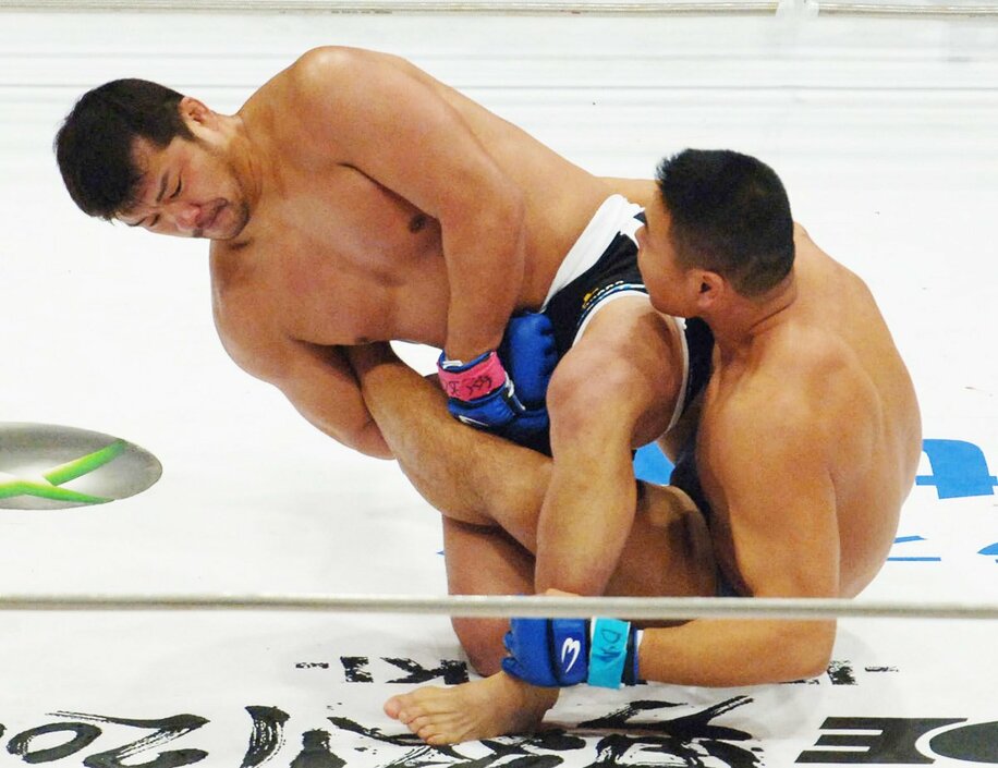  明大の先輩・小川(右)の左足首をロックする吉田（２００５年１２月３１日、さいたまスーパーアリーナ＝東スポWeb）