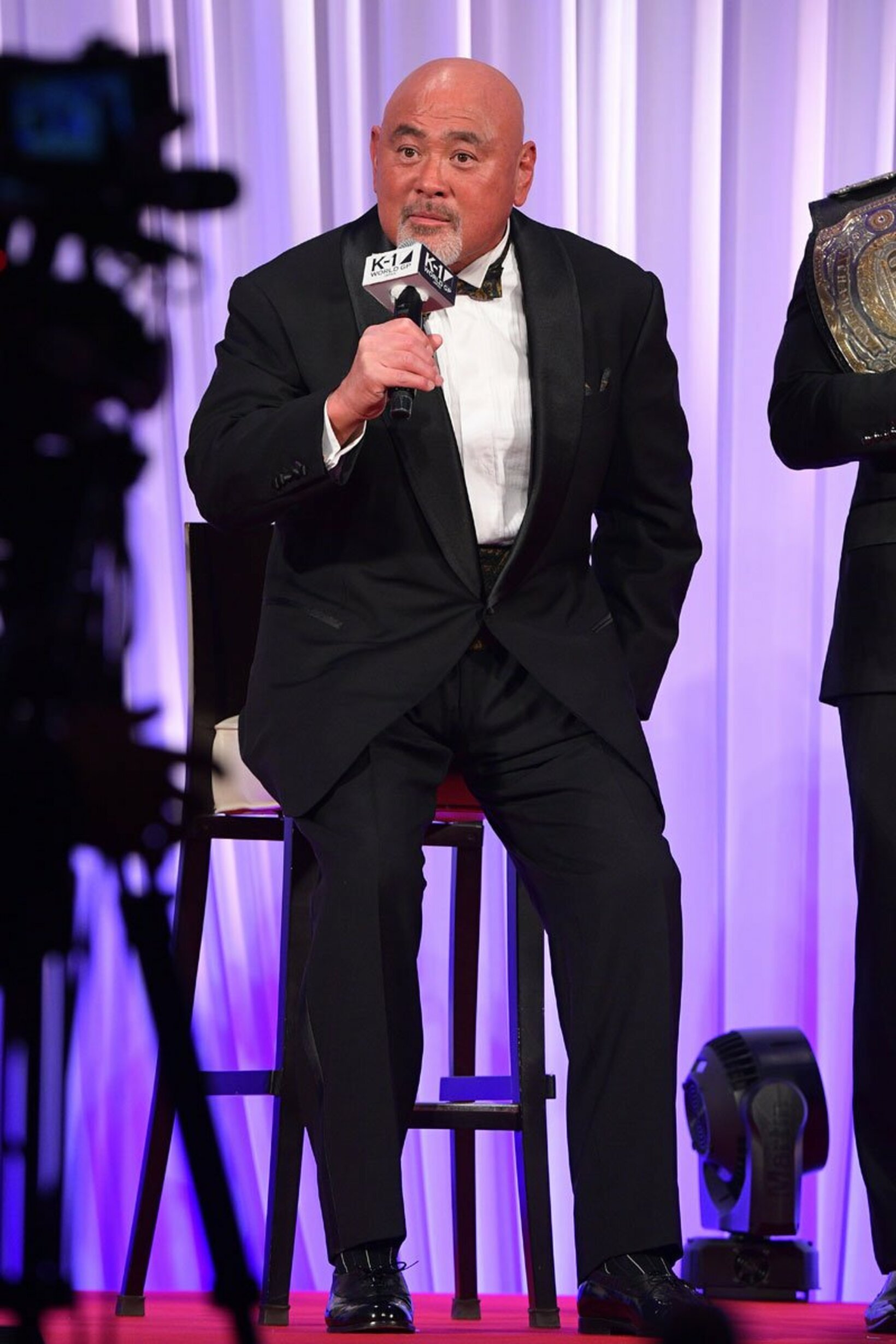 プレゼンターとして登壇し椅子に腰かける武藤