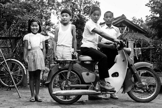 母親のバイクの後ろに立つ小５の谷津嘉章（左から２人目・本人提供）