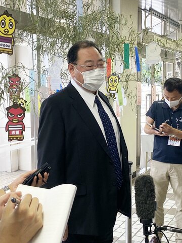  取材を受ける出羽海親方。会場の愛知県体育館には七夕の笹と短冊が飾られている