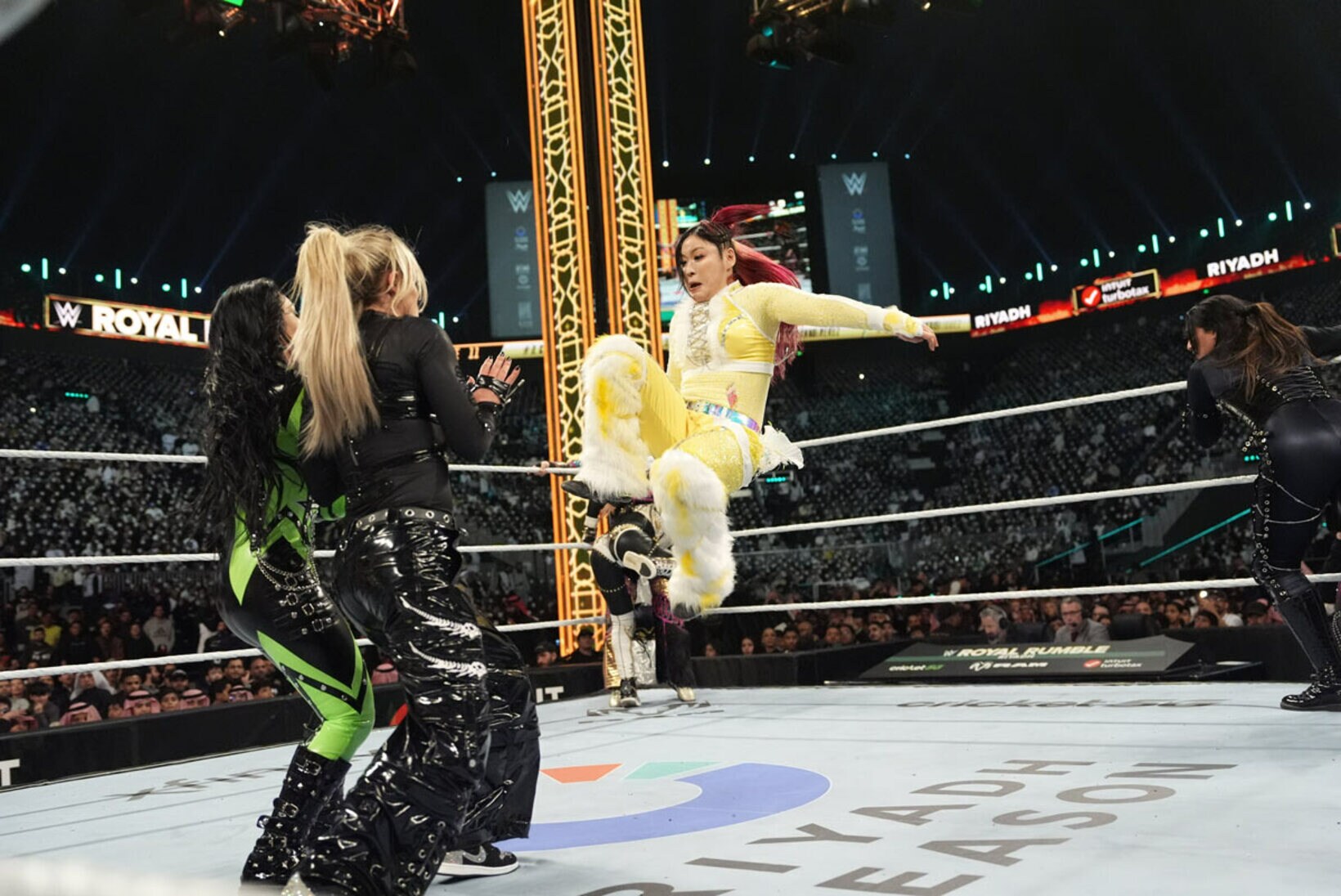 ロクサーヌ・ペレス（左）とリブ・モーガンにまとめてドロップキックを放つイヨ・スカイ©ＷＷＥ