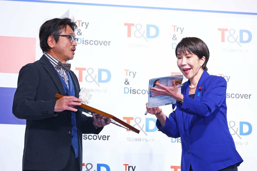 高市首相(右)に年間大賞の表彰を行ったやくみつる氏