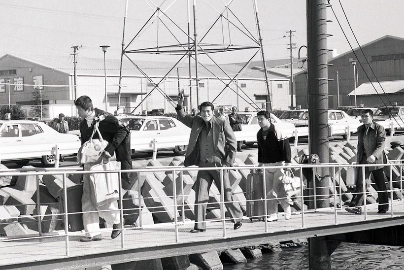 桟橋から手を振る猪木。前を歩くのは前田。猪木の後ろは坂口（右）と付け人の平田（１９７９年１１月、徳島港）