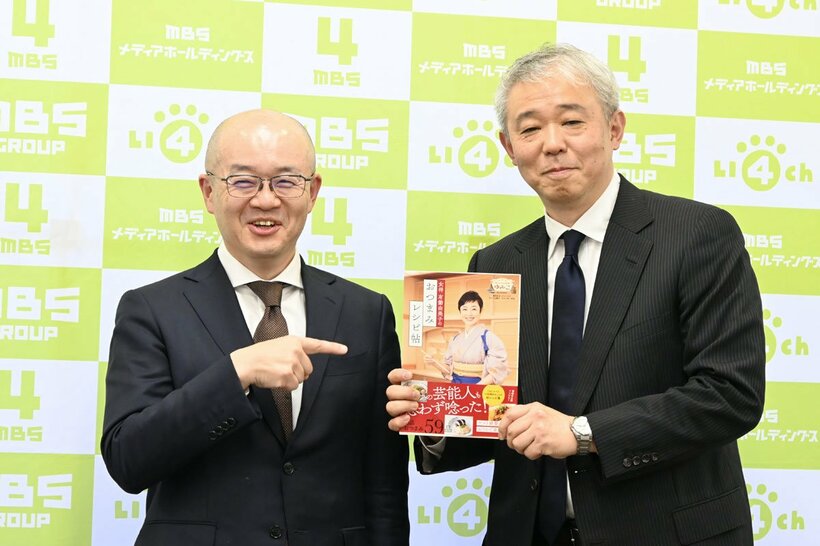 有働のレシピ本を持つ総合編成部長の八木氏（左）と総合編成局長の田淵氏