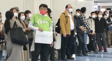  保安検査場前で小室圭さんと眞子さん夫妻を待ち構える観衆の手には「絶対大丈夫」と書かれたカードが