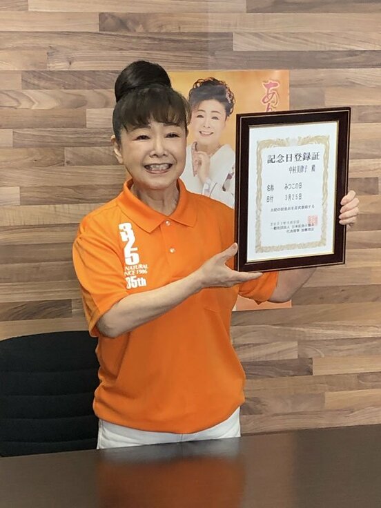  記念日登録証を掲げる中村美律子
