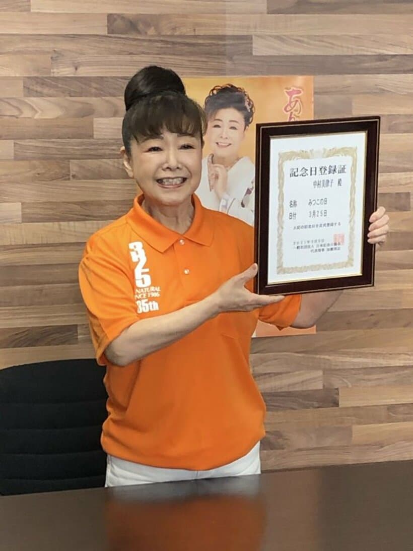  記念日登録証を掲げる中村美律子