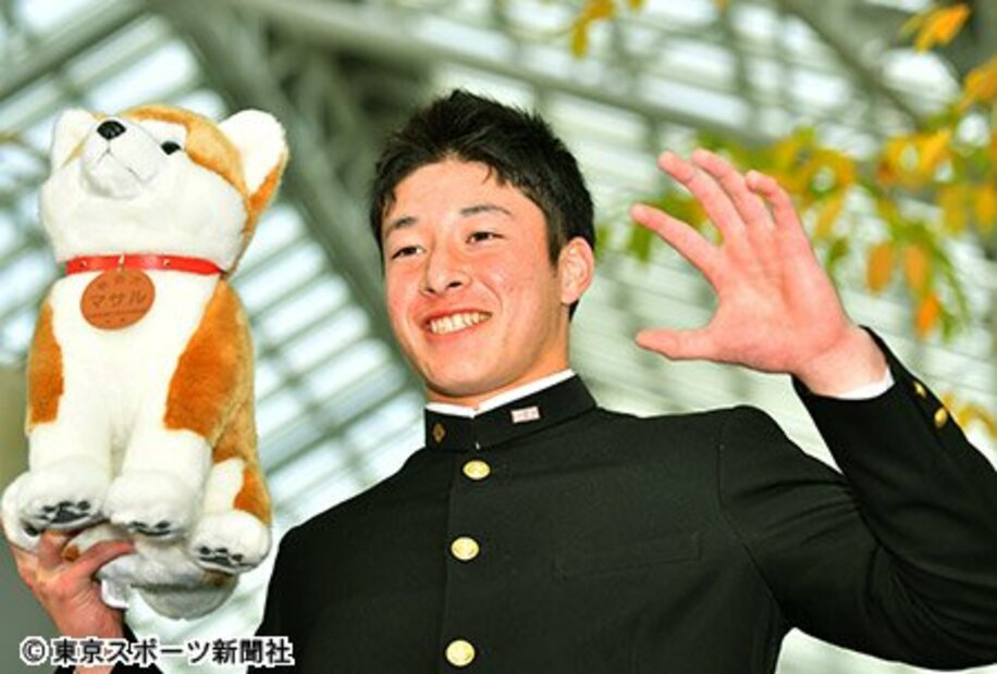  秋田犬の人形を手にポーズを取る吉田