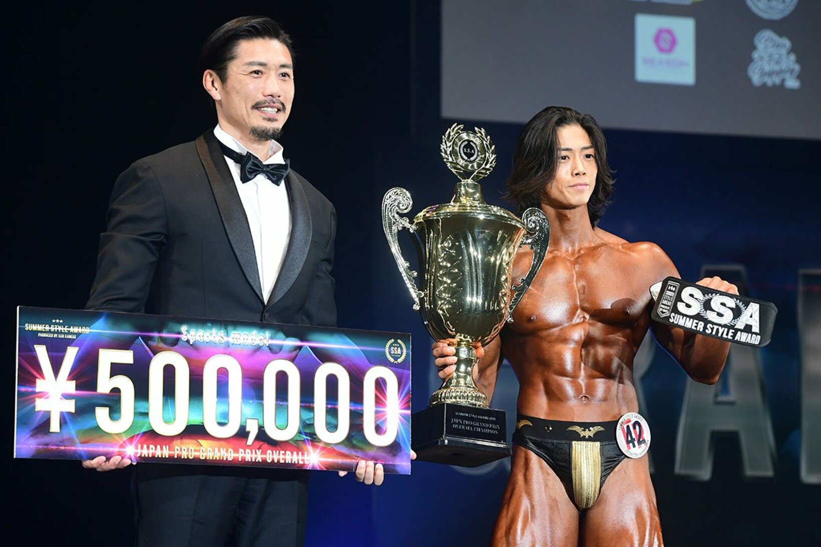 金子賢(左)に優勝の賞金ボードを渡される富樫吏輝