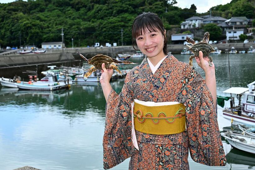 名物・竹崎ガニを両手に笑顔の梅崎恵美さん