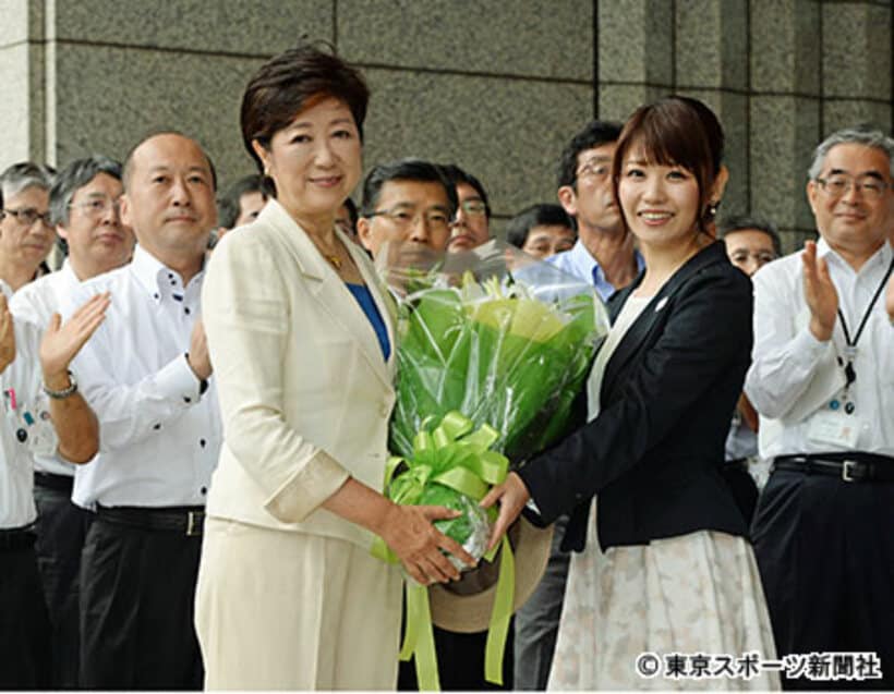 職員に迎えられ花束を贈呈される小池百合子新東京都知事（左）