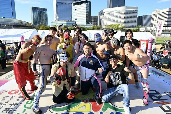 ビル群をバックに、写真に収まるゼウス(前列中央)ら大阪プロレスの面々