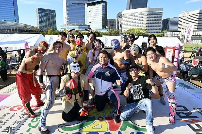 ビル群をバックに、写真に収まるゼウス(前列中央)ら大阪プロレスの面々