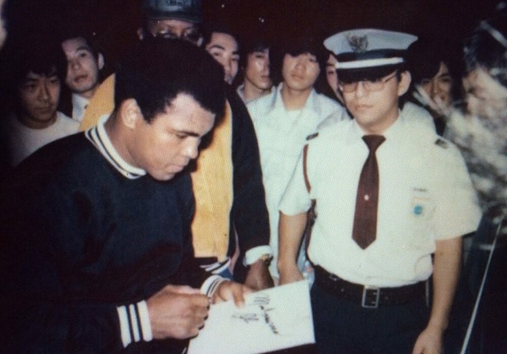 サインするアリ(左)を小川眞澄氏(右)が警護(1976年)