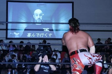カスタニョーリがモニターに登場し真剣な表情で見つめる鷹木信悟