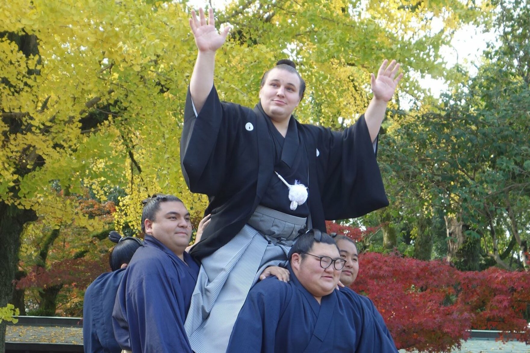 部屋の力士が組む騎馬に乗る安青錦