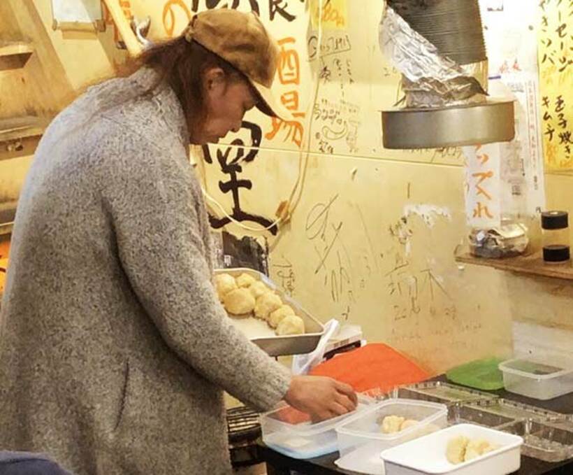  客が持参したタッパーに無料の食事を盛り付ける天野氏