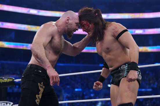 血だるまになりながら、ジョン・モクスリー（左）と頭を突きつけ合う竹下幸之介 ©All Elite Wrestling