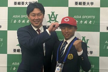 １位指名の亜大・山里（右）に帽子を被せる新井監督