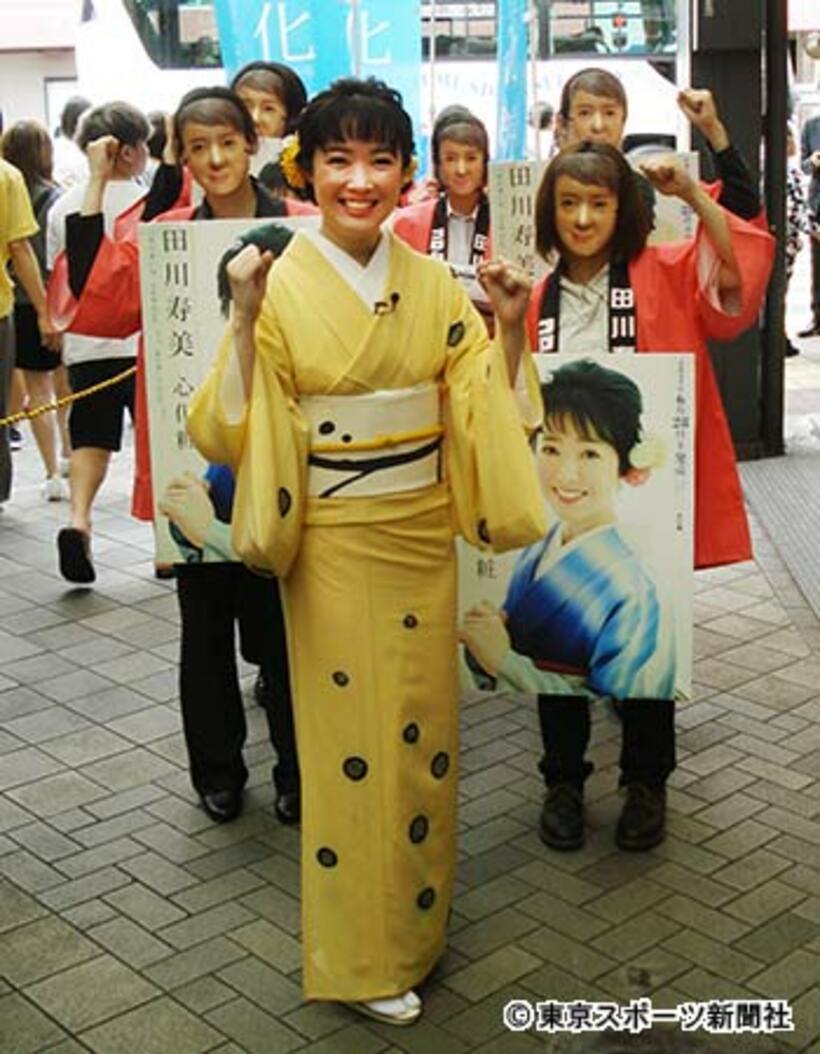 田川のお面をつけた女性スタッフと田川寿美（中央）