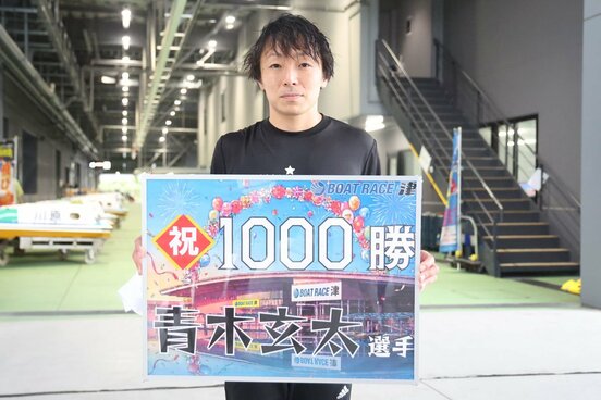 通算1000勝の記念ボードを持つ青木玄太