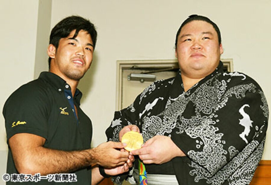 豪栄道（右）は観戦に訪れた大野の金メダルを手に笑顔