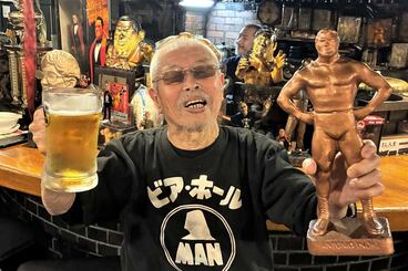 自作の猪木のブロンズ像と生ビールを手にする村田さんは満面の笑み