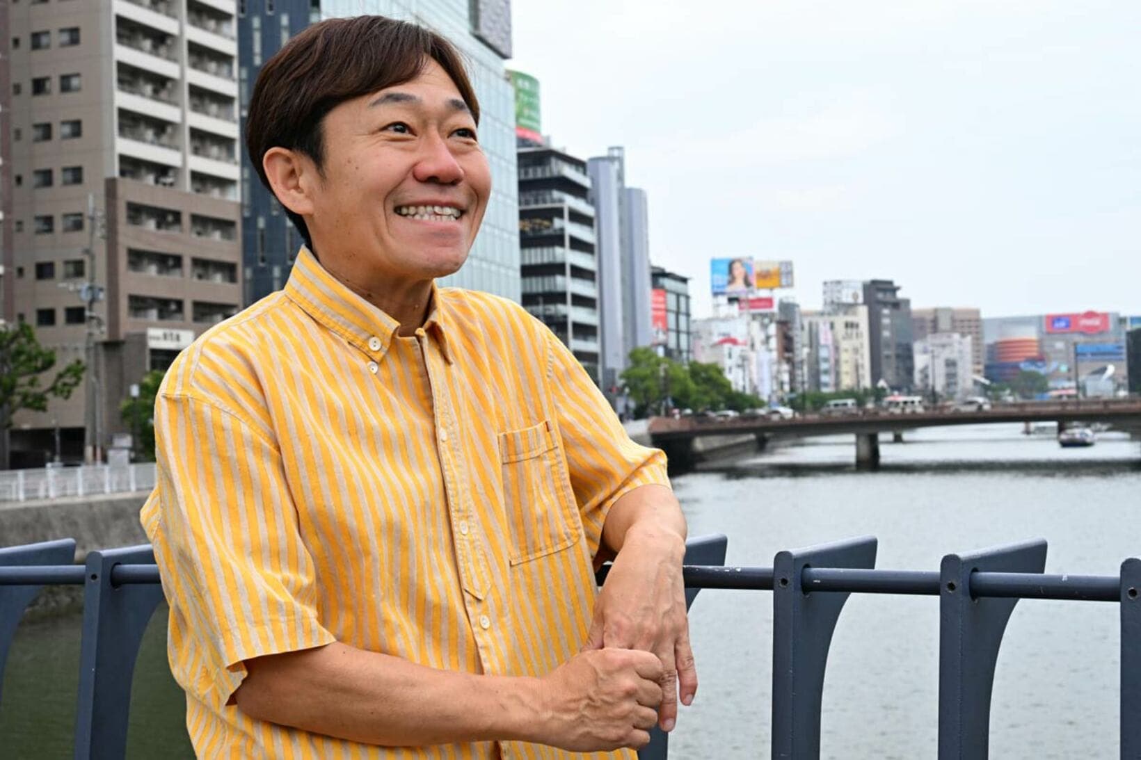 那珂川をバックにポーズを決める田中健二