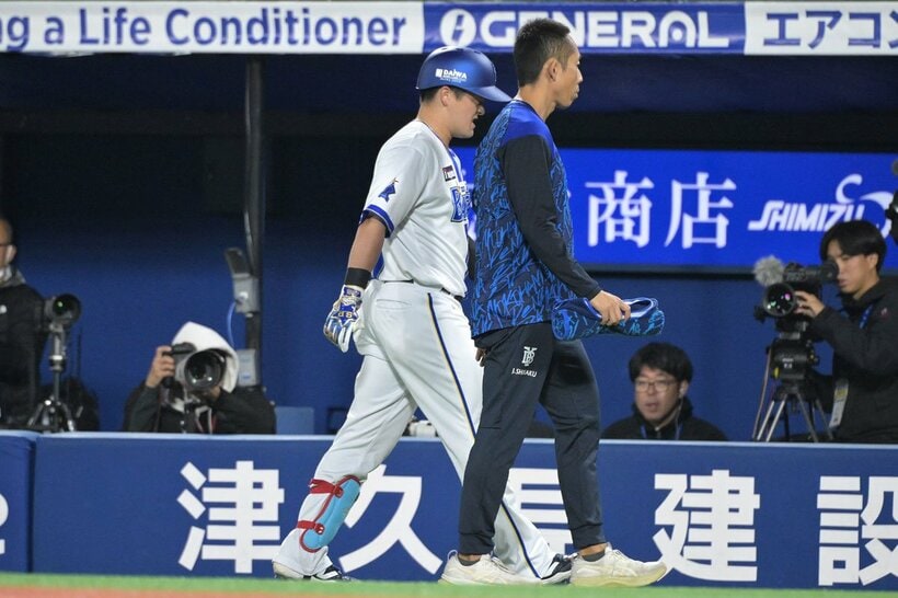 ３回に内野安打を放った後、治療のためベンチに下がるDeNA・牧秀悟(左)