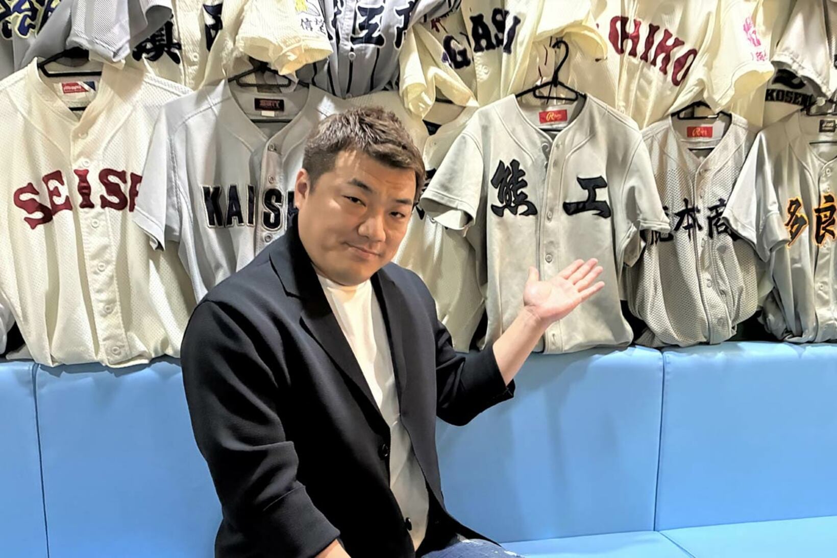 店内に飾られたユニホームを見せる星子崇さん