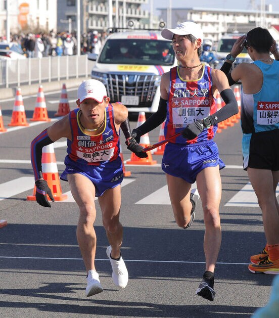  平塚中継所でタスキをつなぐ創価大３区の桑田大輔（右）と４区の嶋津雄大（代表撮影）