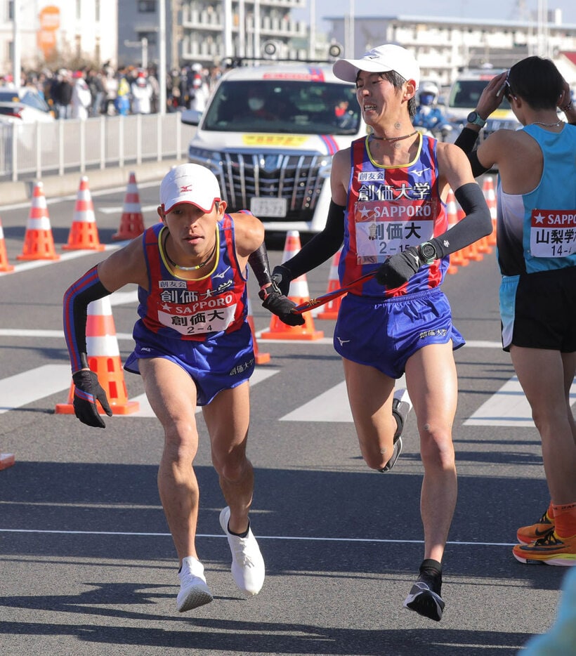  平塚中継所でタスキをつなぐ創価大３区の桑田大輔（右）と４区の嶋津雄大（代表撮影）