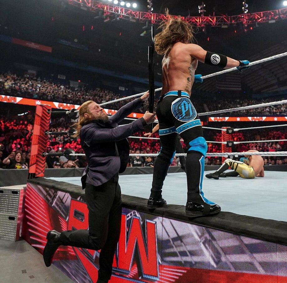  背後に現れたエッジ（左）にパイプ椅子攻撃を浴びたAJスタイルズ（ⓒ2022-WWE,-Inc.-All-Rights-Reserved）