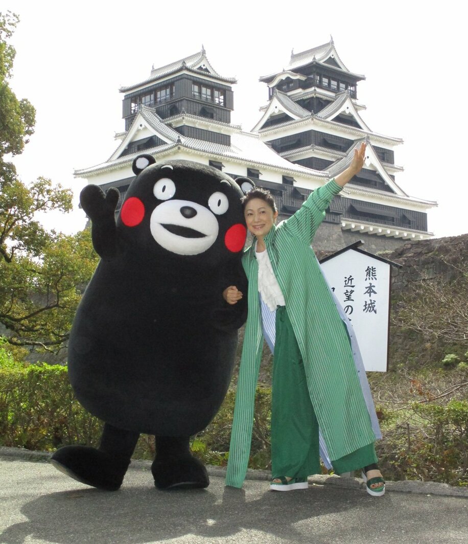  熊本城をバックにくまモンとポーズを決める石川さゆり