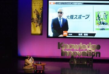 動画プレゼンする吉武支社長(画面)と、それを眺めるオヤジ(左下)