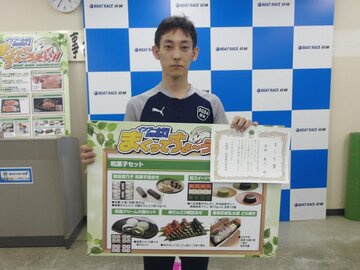 賞品のボードを手に、笑顔の若林義人