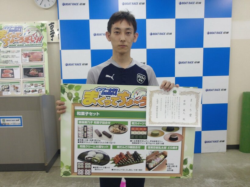 賞品のボードを手に、笑顔の若林義人