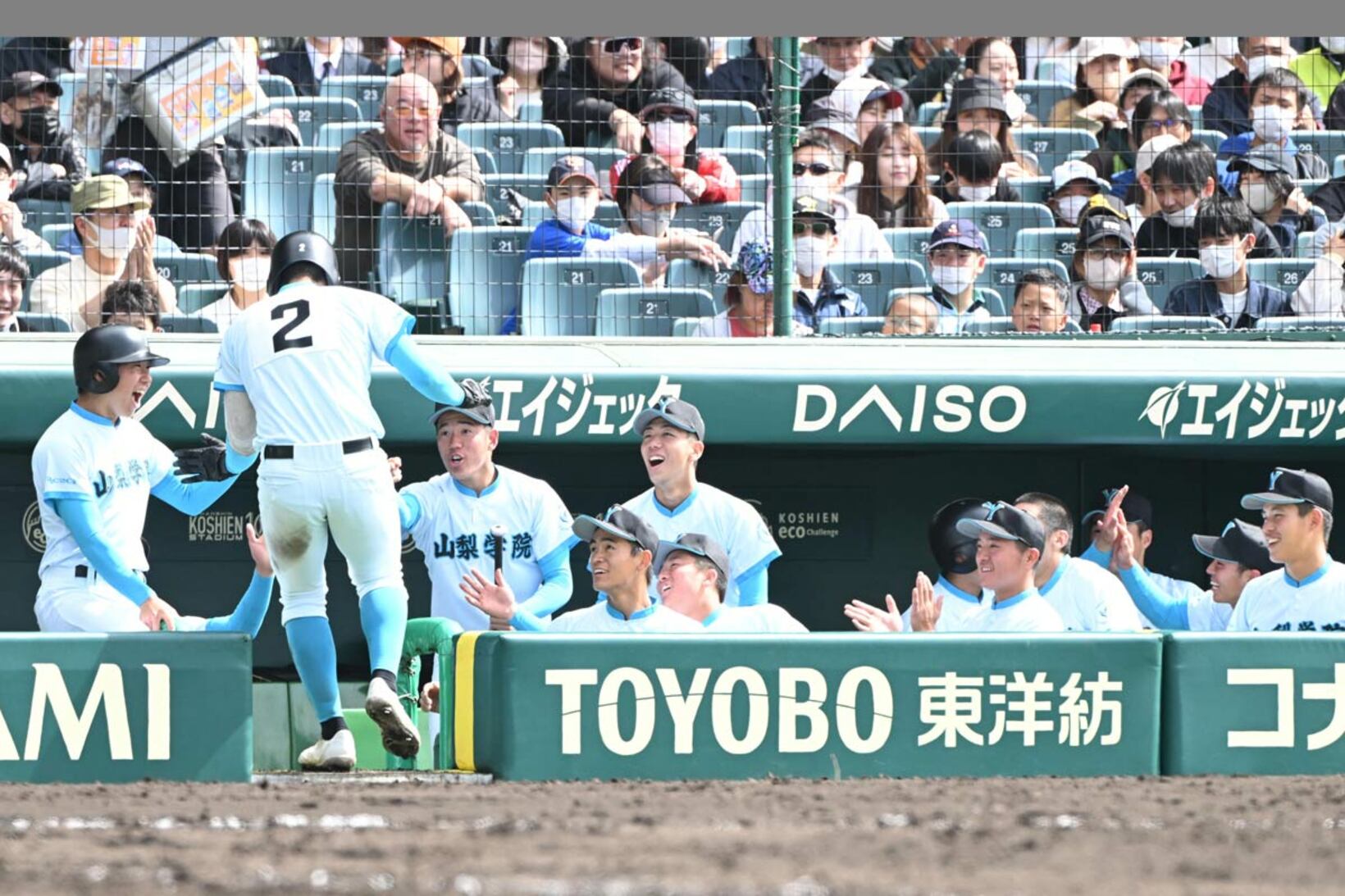 ６回裏、スクイズを決めた佐仲大輝を笑顔で迎える山梨学院ナイン