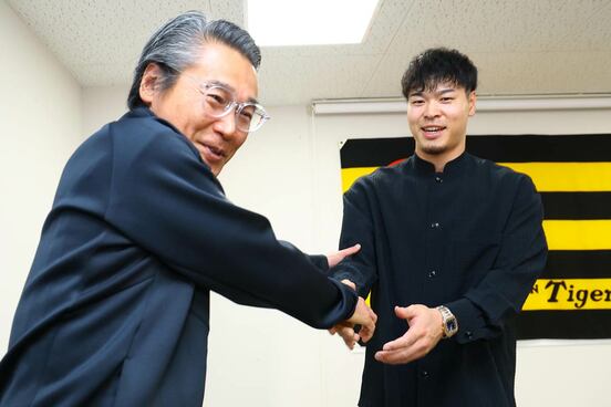 嶌村聡球団本部長(左)と握手を交わす佐藤輝明