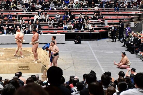 土俵から離れた場所に座り込んで稽古を見る大の里（右）