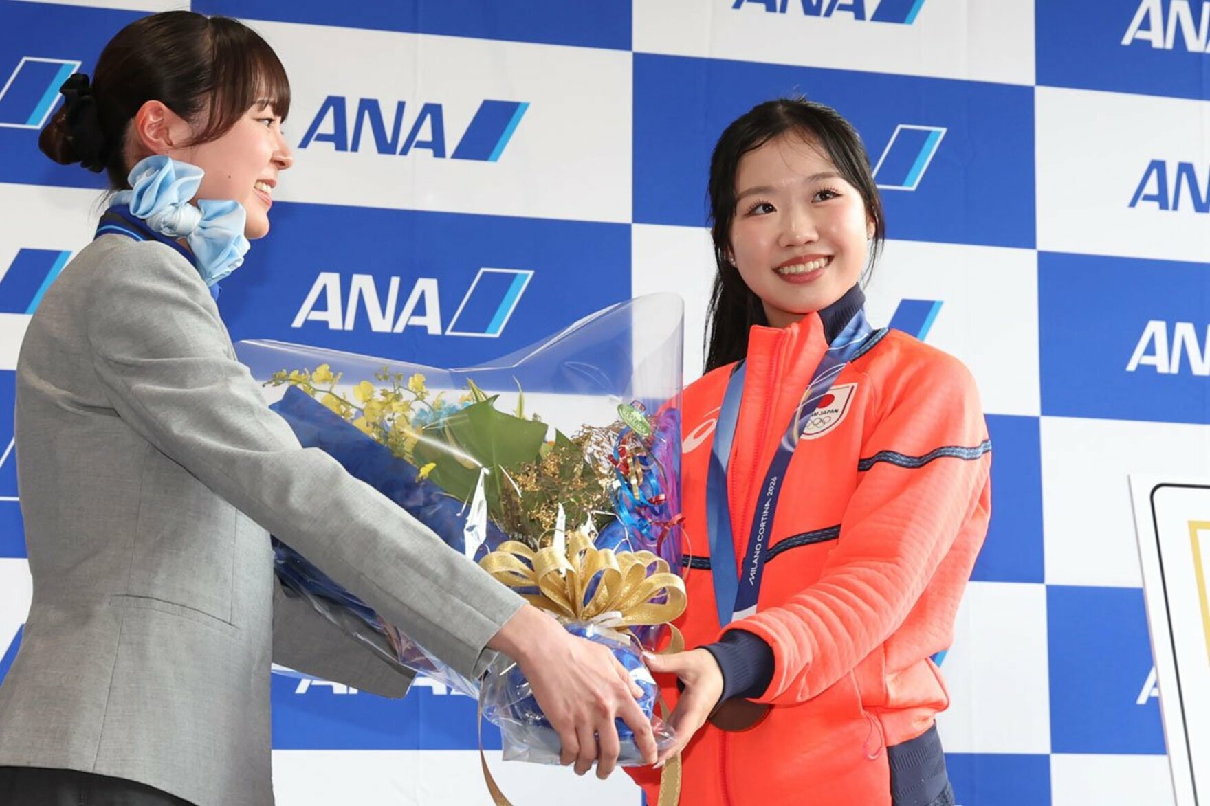 成田空港に帰国し、花束を受け取った中井亜美(右)