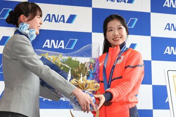 成田空港に帰国し、花束を受け取った中井亜美(右)
