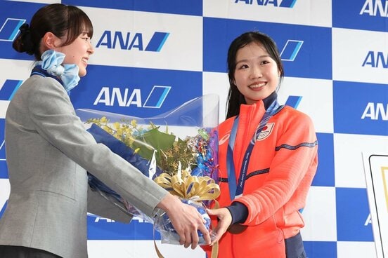 成田空港に帰国し、花束を受け取った中井亜美(右)