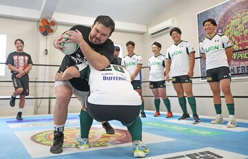 ウルフアロンは若手ラグビー選手にボールを持って突っ込む