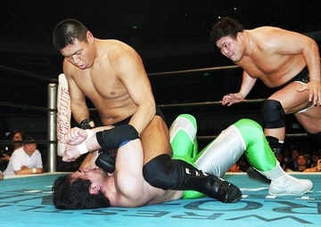 三沢光晴(下)にマウントパンチを見舞う小川直也に、後方からぶちかましを狙う力皇猛（2001年4月、日本武道館）