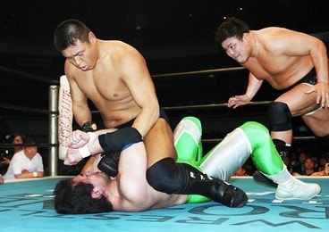 三沢光晴(下)にマウントパンチを見舞う小川直也に、後方からぶちかましを狙う力皇猛（2001年4月、日本武道館）