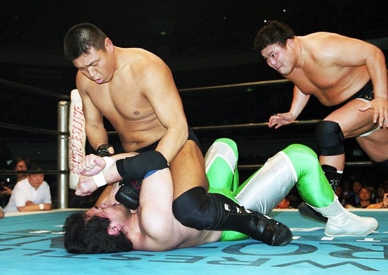 三沢光晴(下)にマウントパンチを見舞う小川直也に、後方からぶちかましを狙う力皇猛（2001年4月、日本武道館）